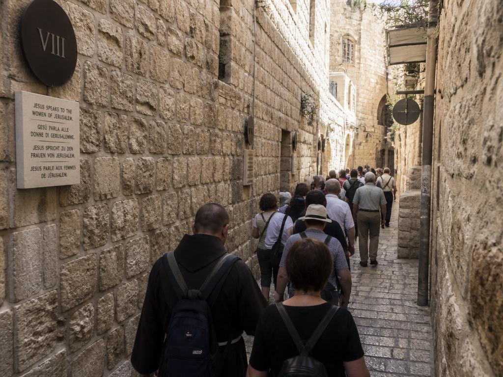 Pilgrims walking the narrow cobblestone Via Dolorosa in Jerusalem's Old City